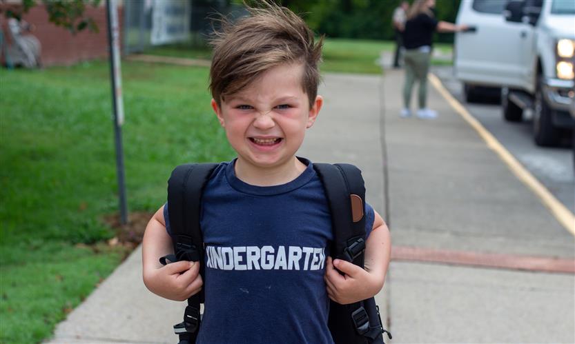 A boy smile while wearing a shirt reading \